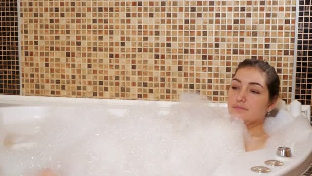 Красивая брюнетка лежит в ванне с пеной — стоковое видео