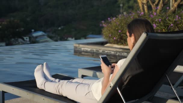 Lány pihen széken sms telefonon a szállodában — Stock videók