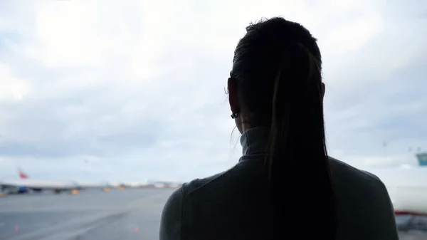 Kobieta z kucykiem patrzy na samoloty na lotnisko fartuch zbliżenie — Zdjęcie stockowe