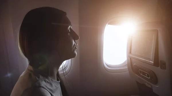 Dziewczyna słucha muzyki w kabinie pasażerskiej samolotu zbliżenie — Zdjęcie stockowe