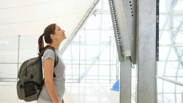 Brunette fille avec sac à dos regarde l'horaire des vols — Photo