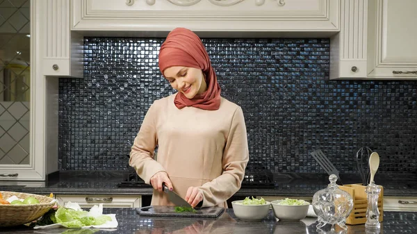 Orientalna kobieta gotuje posiłek cięcia świeżych zieleni uśmiechnięty — Zdjęcie stockowe