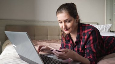 Çekici, uzun saçlı bayan kredi kartlarına ve tiplerine bakıyor.