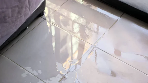 Trembling water puddle covers white tile in house closeup — Stock Photo, Image