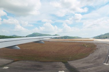 Ön planda kanatları olan uçak pistten kalkıyor..