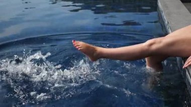 Mavi yüzme havuzunda süzülen genç kadın bacakları