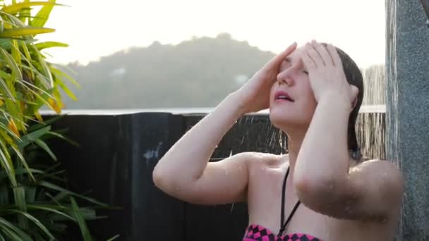 Mädchen im farbigen Bikini fröstelt unter Hoteldusche — Stockvideo