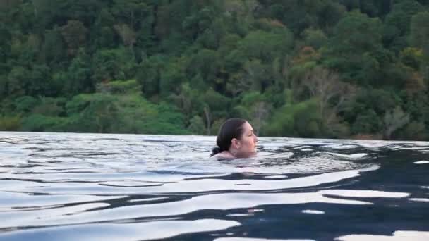 Brunetka plave v hotelovém venkovním bazénu proti rostlinám — Stock video