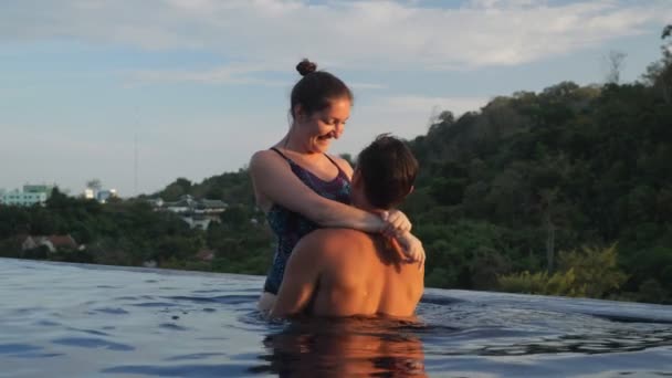 Homem bonito segura senhora nos braços e casal gira na piscina — Vídeo de Stock