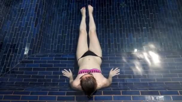 Femme balançant jambes nues avec manucure rouge dans l'eau de piscine — Video