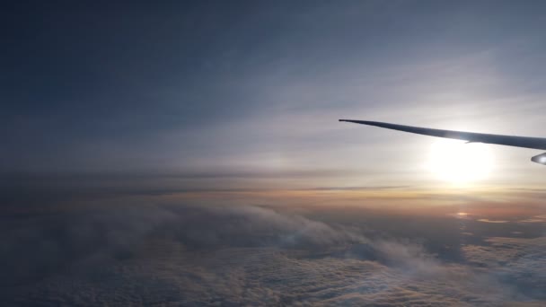 Блестящее солнце на бескрайнем горизонте над облаками под крылом самолета — стоковое видео