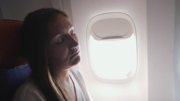 Молодая женщина спит в самолете во время полета — стоковое видео
