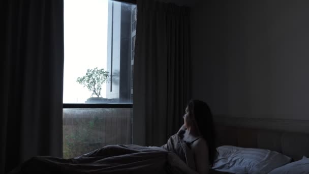 Brunette lady awakes in bed stretching at large hotel window — Stock Video