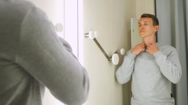 Beau homme en sweat-shirt gris devant un miroir de salle d'essayage — Video