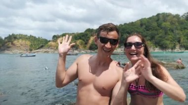 Güneş gözlüklü pozitif aile okyanus sahilinde el sallıyor.