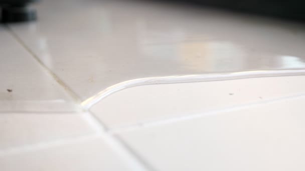 Вода розкладається по підлозі білою плиткою, що відображає вікно — стокове відео