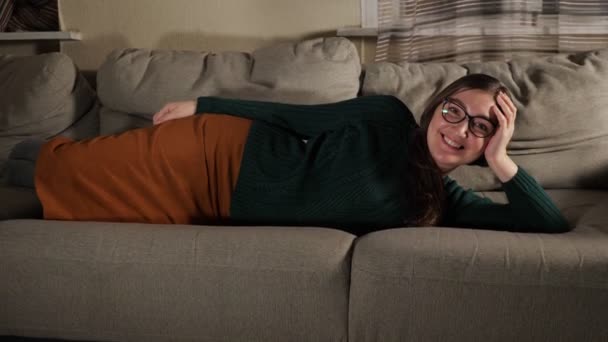 Mladá žena leží na pohovce v obývacím pokoji — Stock video
