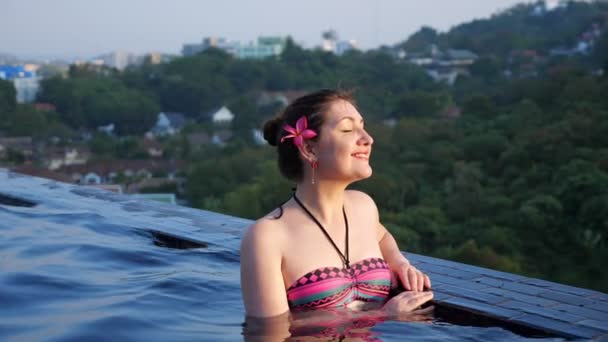 Atraente morena sorrisos alegremente refrigeração na piscina — Vídeo de Stock