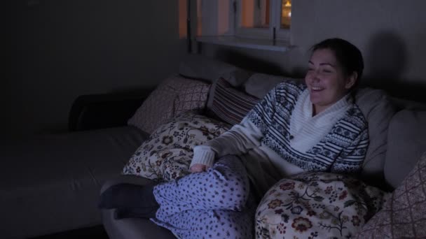 어둠 속에서 웃긴 영화를 보고 있는 젊은 여자 — 비디오