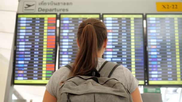 Брюнетка рассматривает расписание вылетов в терминале аэропорта — стоковое видео