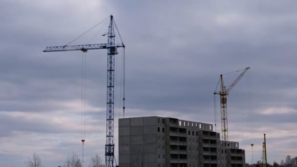 Stavební jeřáby a nová budova uprostřed temných nízkých mraků — Stock video