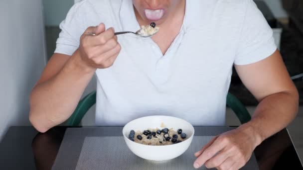 Tipo reconocible en camiseta blanca come deliciosos cereales gachas — Vídeos de Stock