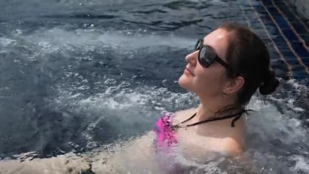 Giovane donna in bikini viola si rilassa nella piscina idromassaggio all'aperto — Video Stock
