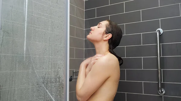 Mujer joven con largo pelo mojado suelto se levanta bajo la ducha — Foto de Stock