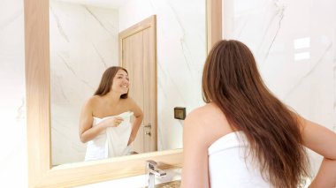 Genç bir kadın dişlerini beyaz diş fırçasıyla fırçalıyor.