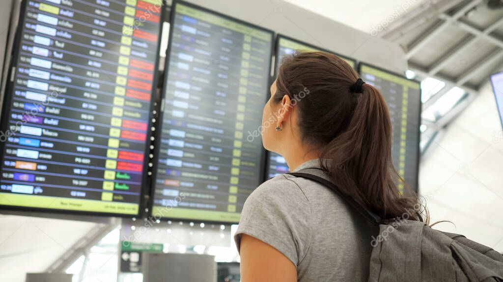 brunette looks at departures schedule in airport terminal