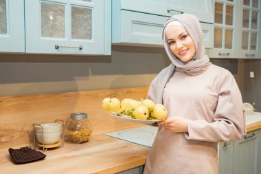 Modern mutfakta bir kase armudu olan güzel Müslüman kadın.