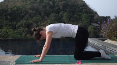 Yogadaki genç kadın kedi-inek pozu veriyor. Açık hava aktiviteleri