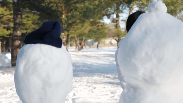 Alegre negro dama pasa tiempo libre entre los muñecos de nieve en parque — Vídeo de stock