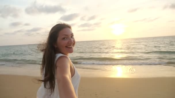 Donna sorridente corre tenendo mano fidanzato lungo la costa dell'oceano — Video Stock