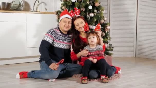 幸せな家族はセットでポーズクリスマスツリーの近くの床に座っている — ストック動画