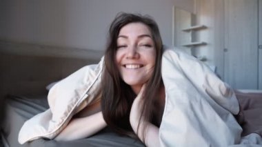 Güzel kız, otel odasındaki büyük yatakta battaniyeye saklanır.