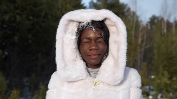 Menina negra feliz em capuz de pele recebe bola de neve na cara sorrindo — Vídeo de Stock