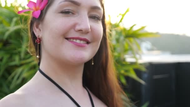Brunette avec fleur dans de longues poses de cheveux lâches avec sourire — Video