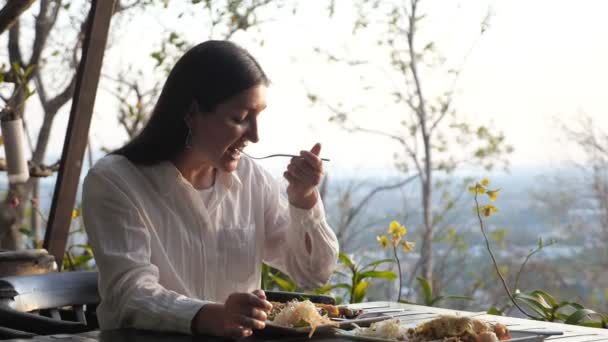 Jovem mulher em uma camisa branca está jantando ao ar livre — Vídeo de Stock