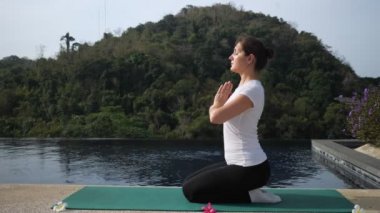 Yoga temiz havada. Genç bir kadın havuz kenarında meditasyon yapıyor.