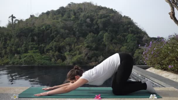 Morena mujer en ropa deportiva hace estiramiento cerca de la piscina al aire libre — Vídeos de Stock