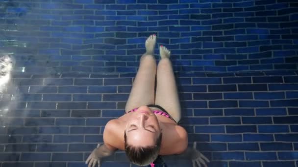 Brunette siège dans l'eau transparente de la piscine de l'hôtel — Video