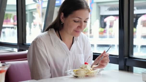 Mladá žena jíst zmrzlinu v kavárně — Stock video