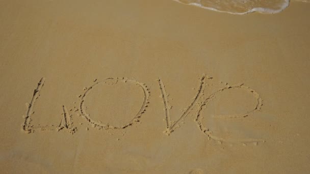 Inschrift im Sand. Meereswelle spült das Wort Liebe weg — Stockvideo