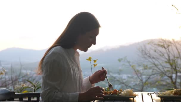 Brunette vrouw aan het eten in een café met een prachtig uitzicht — Stockvideo