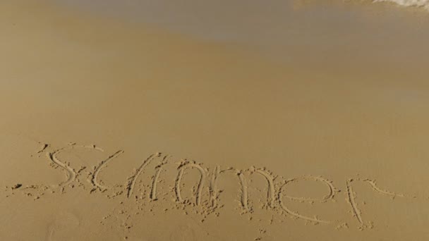 Napis na piasku. Fala morska wymazuje słowo lato — Wideo stockowe