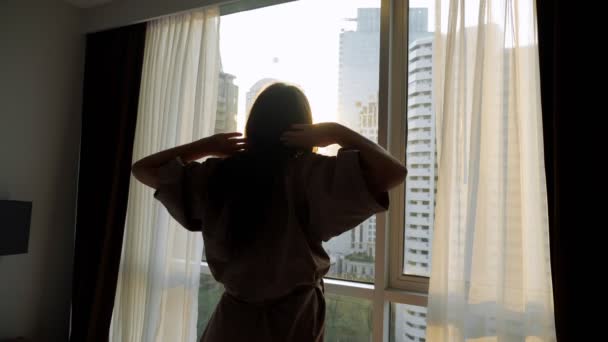 Silhueta de mulher olhando para arranha-céus fora da janela — Vídeo de Stock