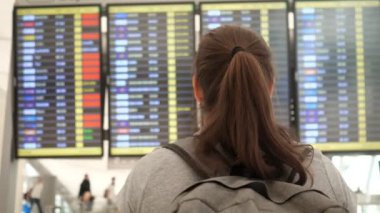 Atkuyruklu kadın havaalanındaki uçuş programını inceliyor.