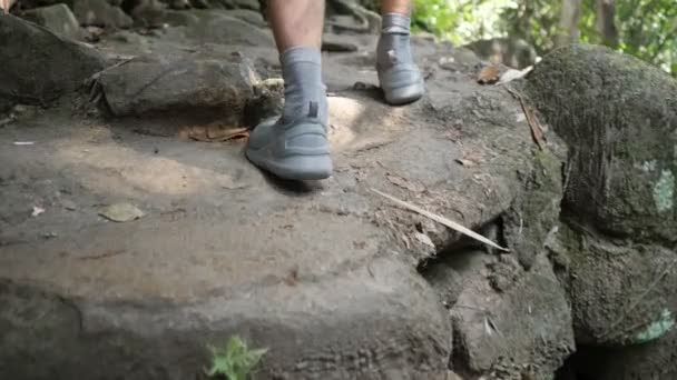 Männerfüße in Turnschuhen und Socken wandern steilen Steinaufstieg entlang — Stockvideo