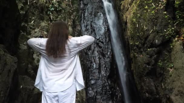 Jeune femme brune lève les bras contre la cascade — Video